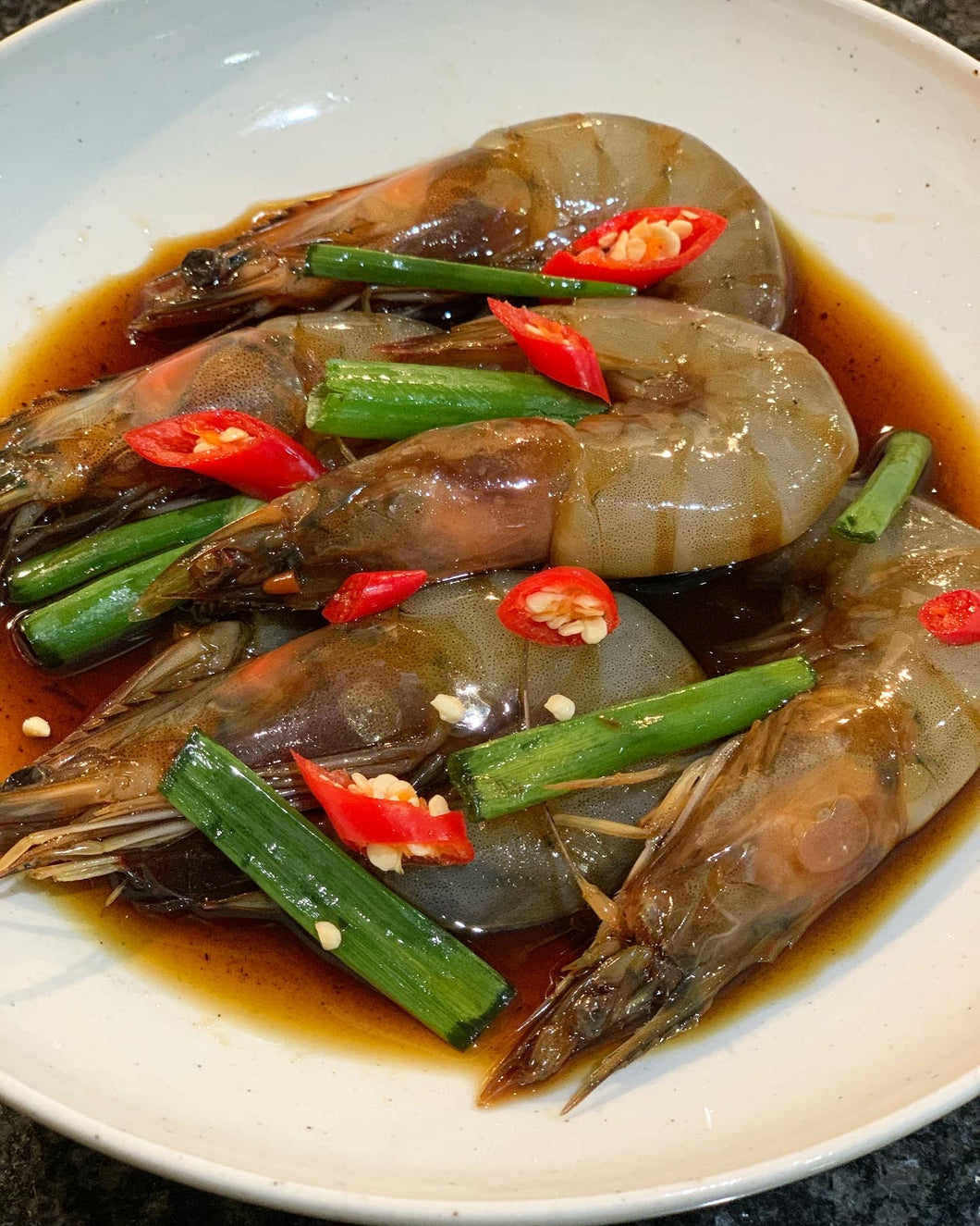 A plate of shrimps marinating in soy sauce